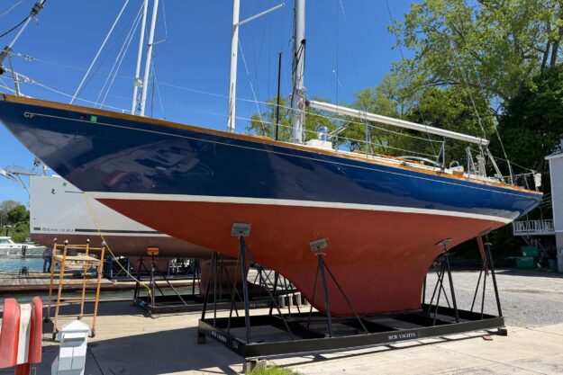 1969 Hinckley 41 sailboat on dry dock, blue hull, red keel, sunny day.