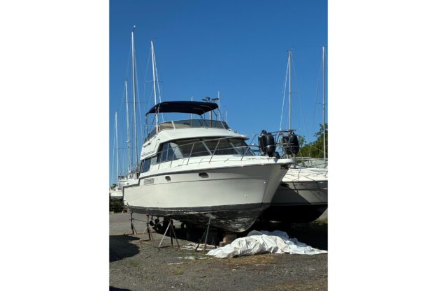 1995 Carver 370 Voyager yacht on dry dock under clear blue sky.