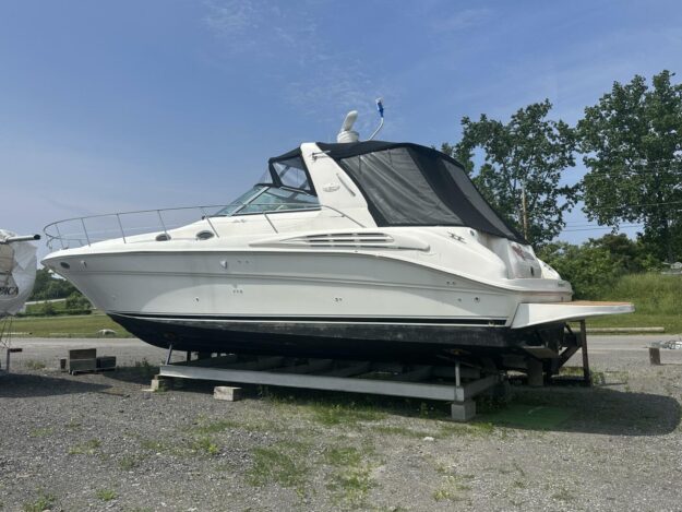 1999 Sea Ray 400 Sundancer yacht on dry dock, side view, under clear blue sky.