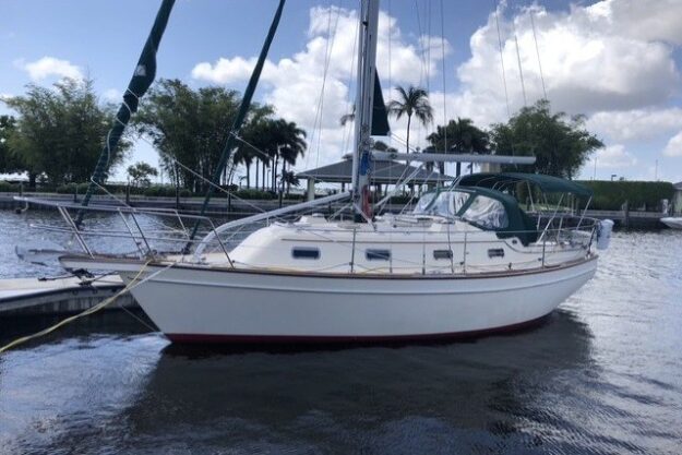 Sailboat docked at marina, Island Packet 320, year 2000, under a partly cloudy sky.