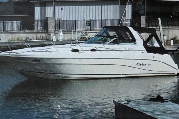 2000 Rinker 340 Fiesta Vee boat docked in marina, side view.