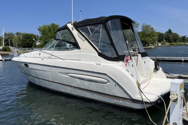 2001 Maxum 3300 SCR boat docked in a marina, featuring sleek design and American flag.