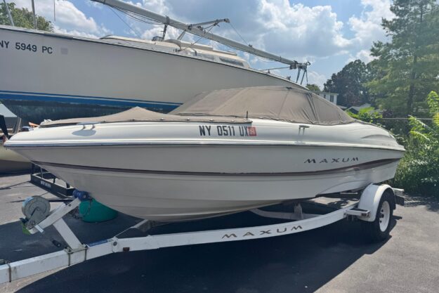 2002 Maxum 1800 SR boat on trailer, parked outdoors under a cloudy sky.