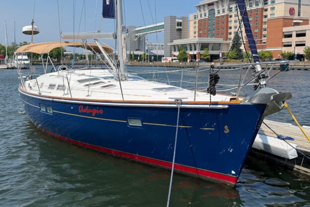 Sleek 2006 Beneteau 423 sailboat docked in a marina, featuring a blue hull and tan canopy.
