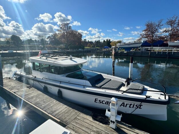 Axopar 37 Cross Cabin BRABUS 2020 docked, sunny day, calm water, “Escape Artist” on side.