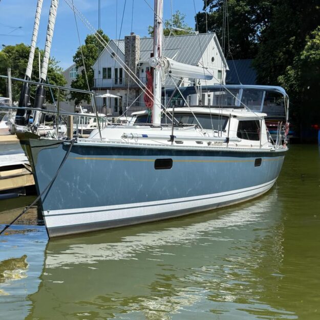 2024 Tartan 455 sailboat docked in a marina, surrounded by trees and buildings.