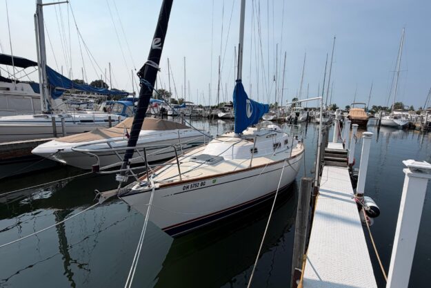 Sailboat docked at marina, Tartan 28 Piper, 1991 model, calm waters, clear sky.