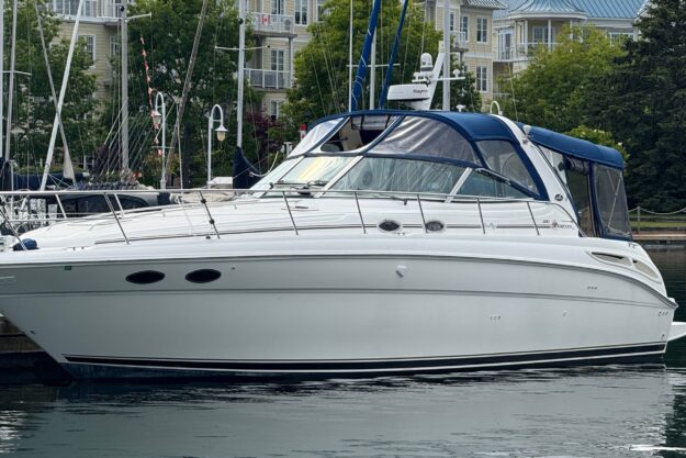 2000 Sea Ray 380 Sundancer yacht docked in a marina, surrounded by buildings and greenery.