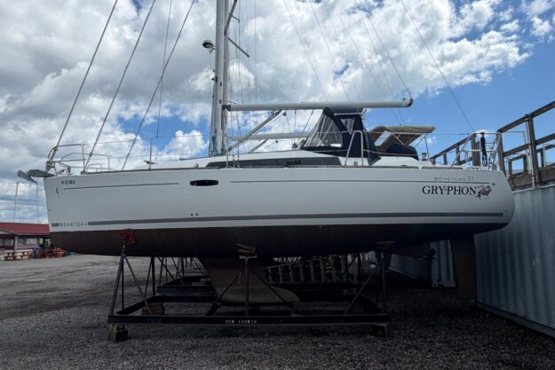 2009 Beneteau Oceanis 31 sailboat on dry dock under cloudy sky.