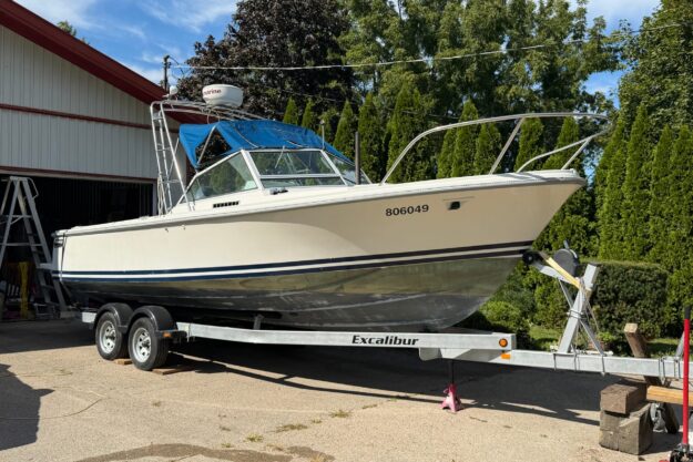 1986 Limestone 24 Runabout boat on trailer, parked outdoors near trees and a building.