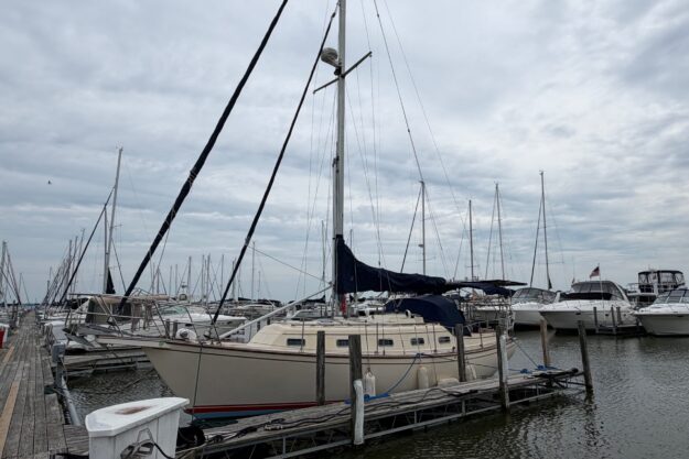 1990 Island Packet 32 sailboat docked at a marina under cloudy skies.