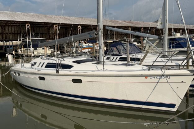 Sailboat docked at marina, 1997 Hunter 376 model, white hull, calm water reflection.