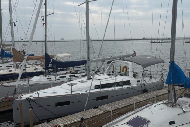 2015 Beneteau Oceanis 38 sailboat docked at marina on a cloudy day.
