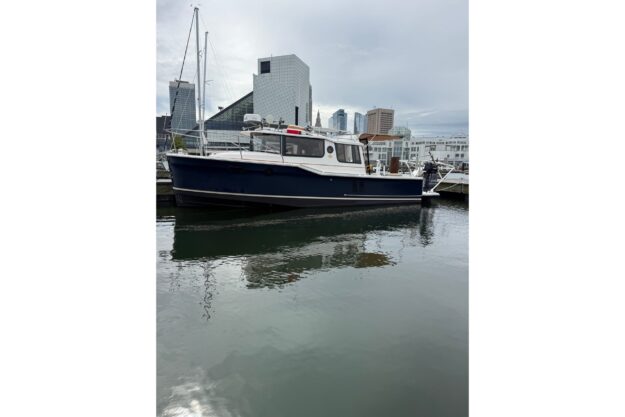 2021 Ranger Tugs R-27 boat docked in urban marina setting.