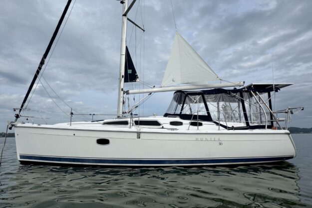 2009 Hunter 36 sailboat on calm water under cloudy sky.