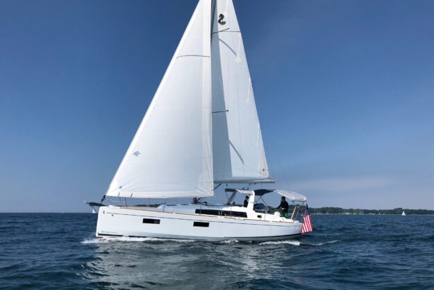 2018 Beneteau Oceanis 38.1 sailing on open water under clear blue skies.
